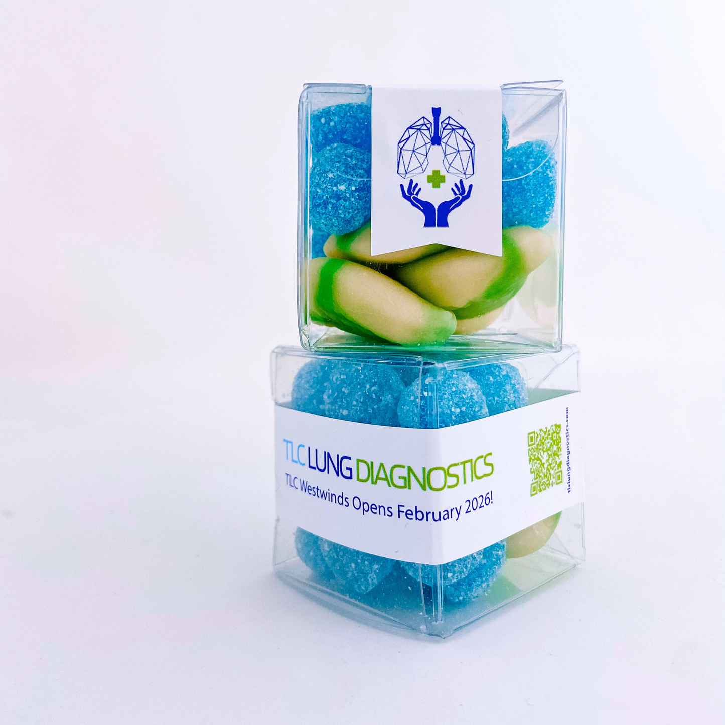 Two stacked clear CandyGrams filled with a coordinated blue and green candy mix, displaying the wraparound grand opening sticker for TLC Lung Diagnostics.