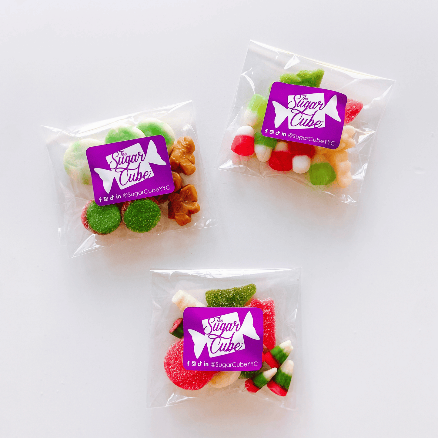 Group of three festive holiday candy bags filled with colourful Christmas sweets, sours and gummies
