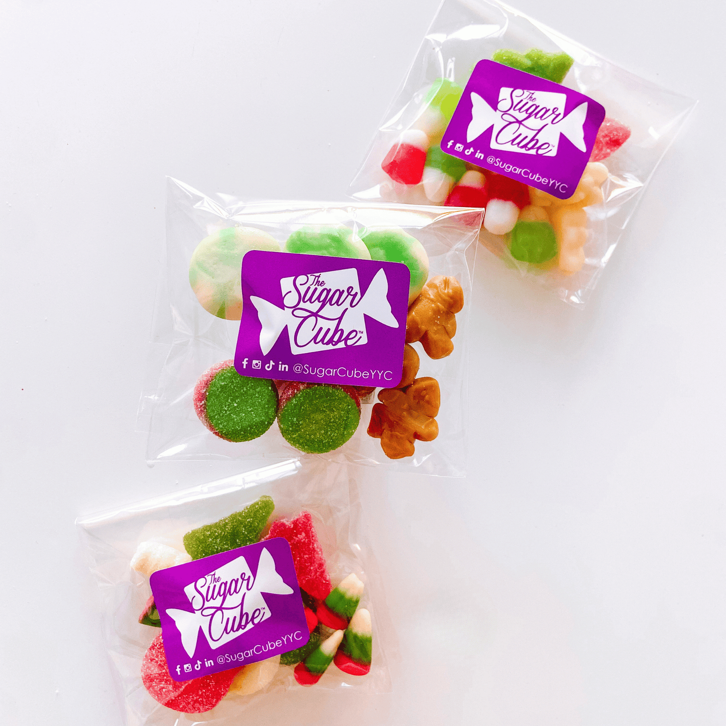 Three Spread the Cheer Christmas candy bags filled with festive red, green and white assorted sweets