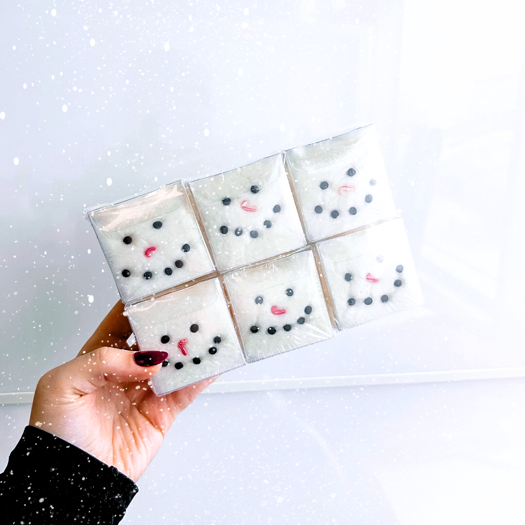 Six Marshmallow Snowman hot chocolate cotton candy bombs made with marshmallow cotton candy, marshmallows and cookie bits