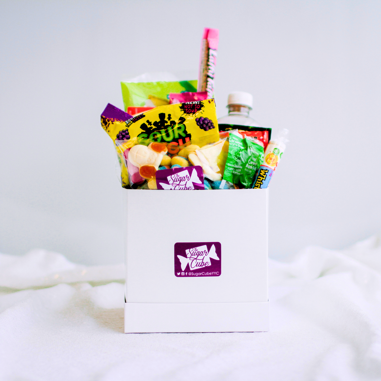Medium candy gift basket with approximately 10 to 15 assorted treats and a specialty soda bottle